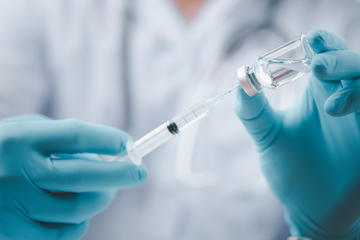 A doctor holding a vaccine dose © LookerStudio/Shutterstock